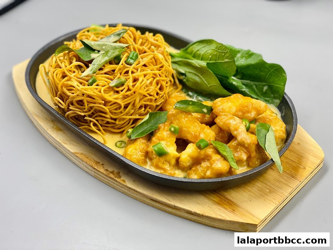 A sizzling platter of crispy noodles and creamy butter chicken with fresh greens.