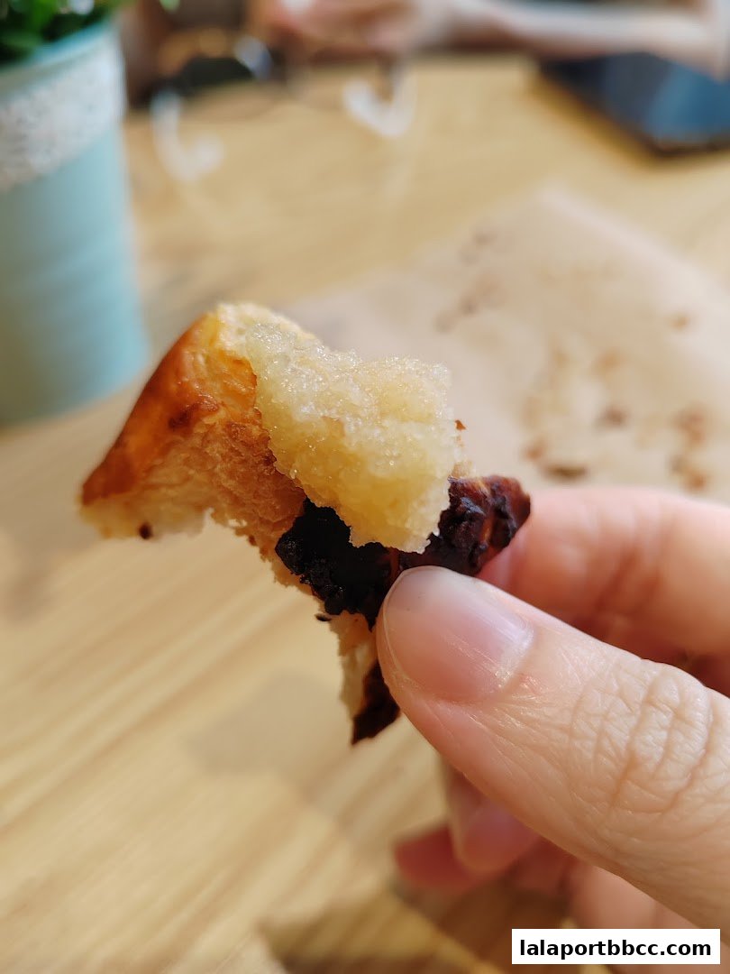 A close-up of a person holding a piece of pastry with a sugary topping.