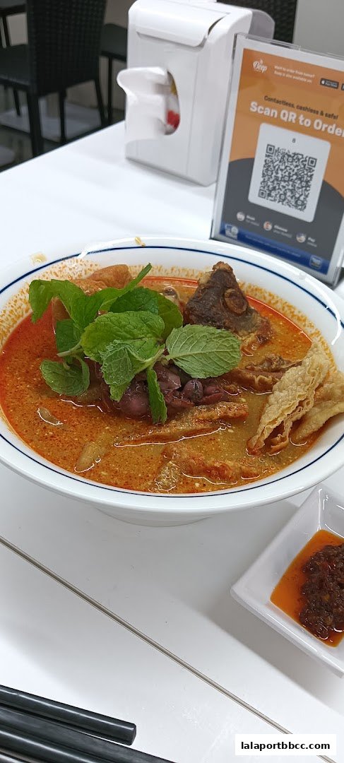 A bowl of delicious Hong Kong-style curry noodles with fresh mint and a side of chili paste.
