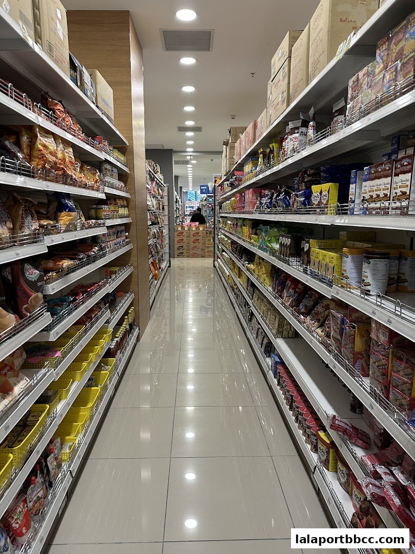 A long aisle of shelves stocked with various food and household products in a MR.DIY PLUS store.