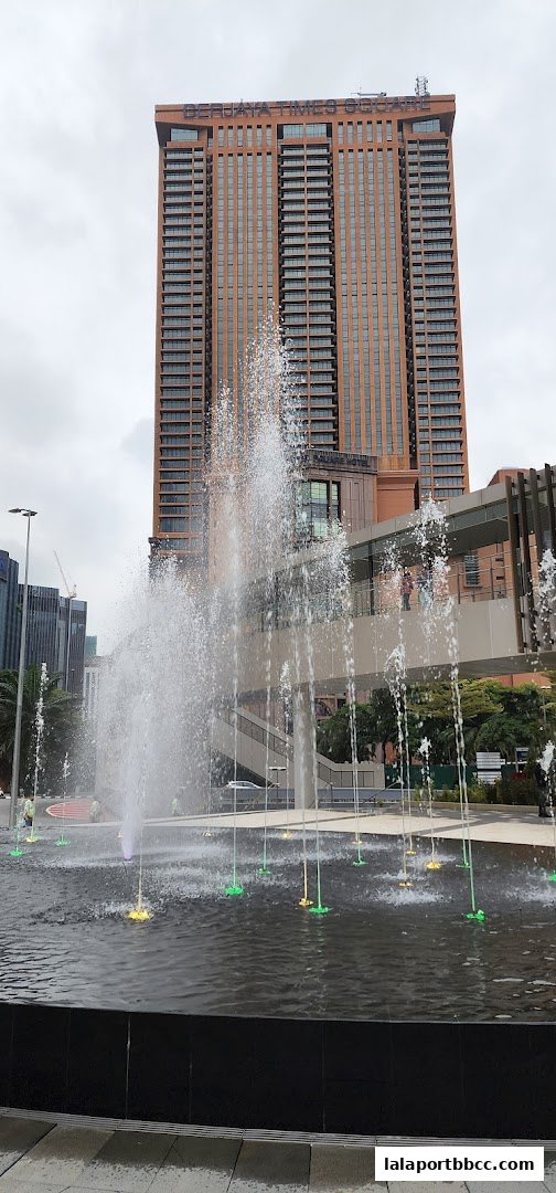 A large fountain with colorful lights in front of a tall, modern building.