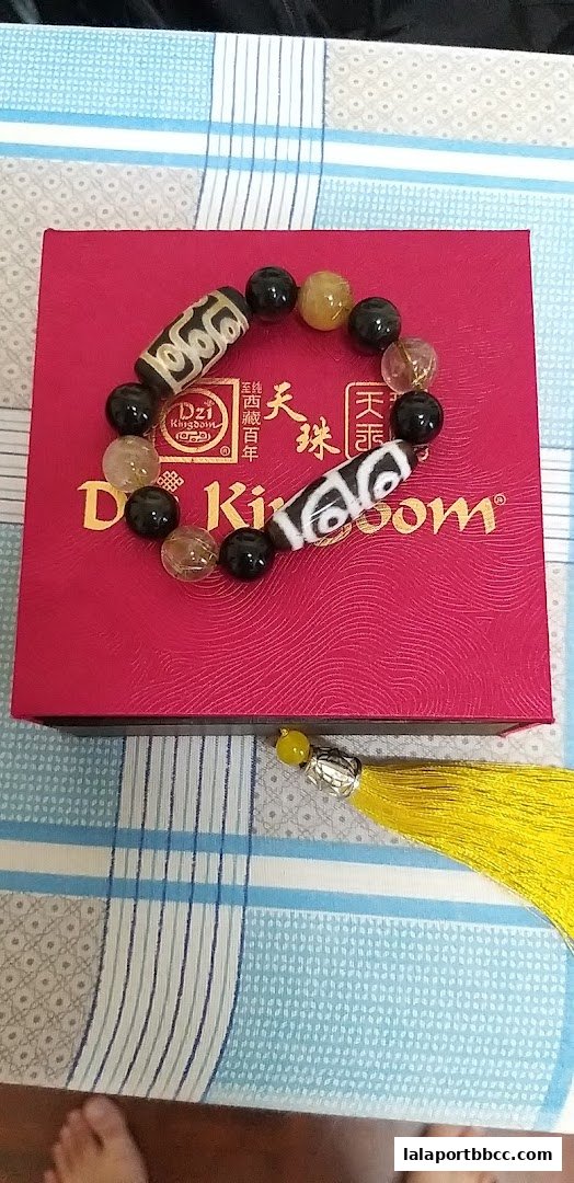 A Dzi Kingdom bracelet with black, clear, and yellow beads on a red box.