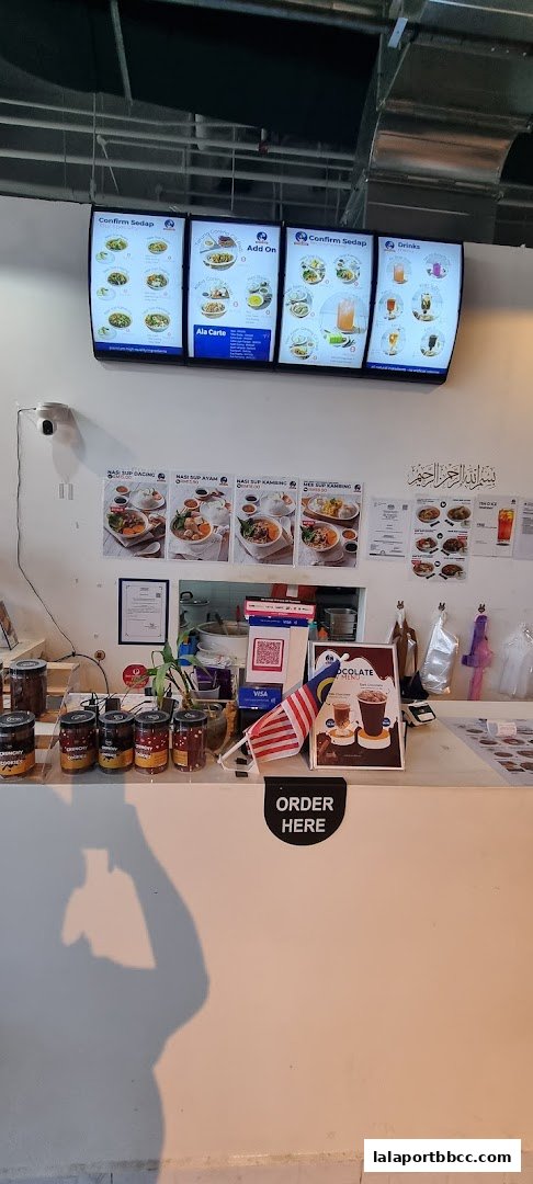 A counter area with digital menus, food posters, and jars of cookies.
