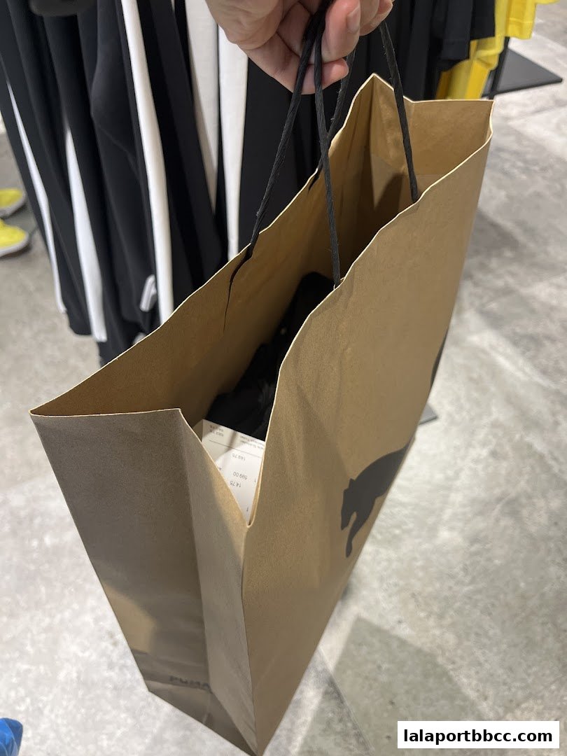 A person holds a PUMA shopping bag with a receipt visible inside.