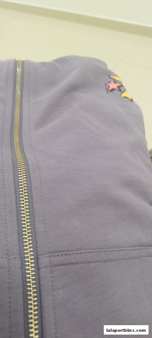 Close-up of a grey Converse hoodie with a zipper and star graphic.