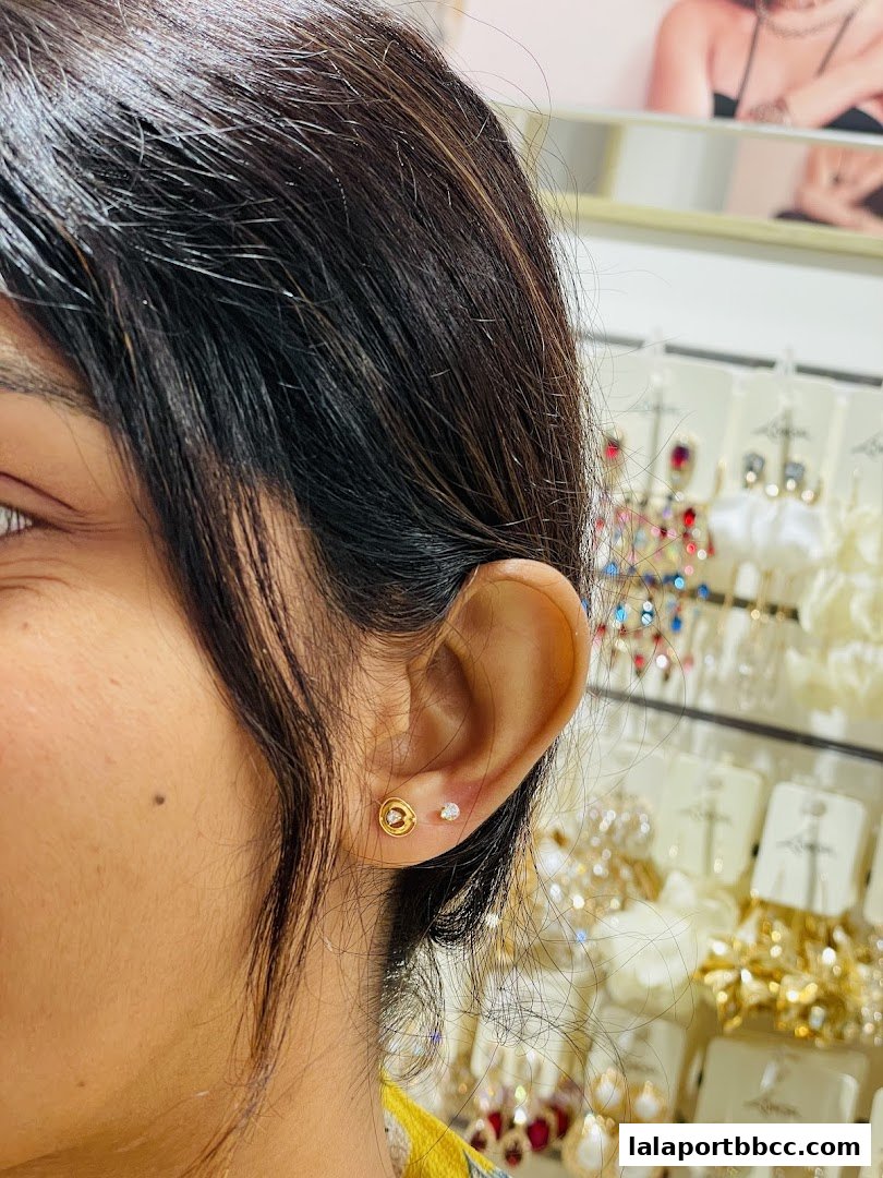 Close-up of a woman's ear showcasing delicate gold and diamond stud earrings.
