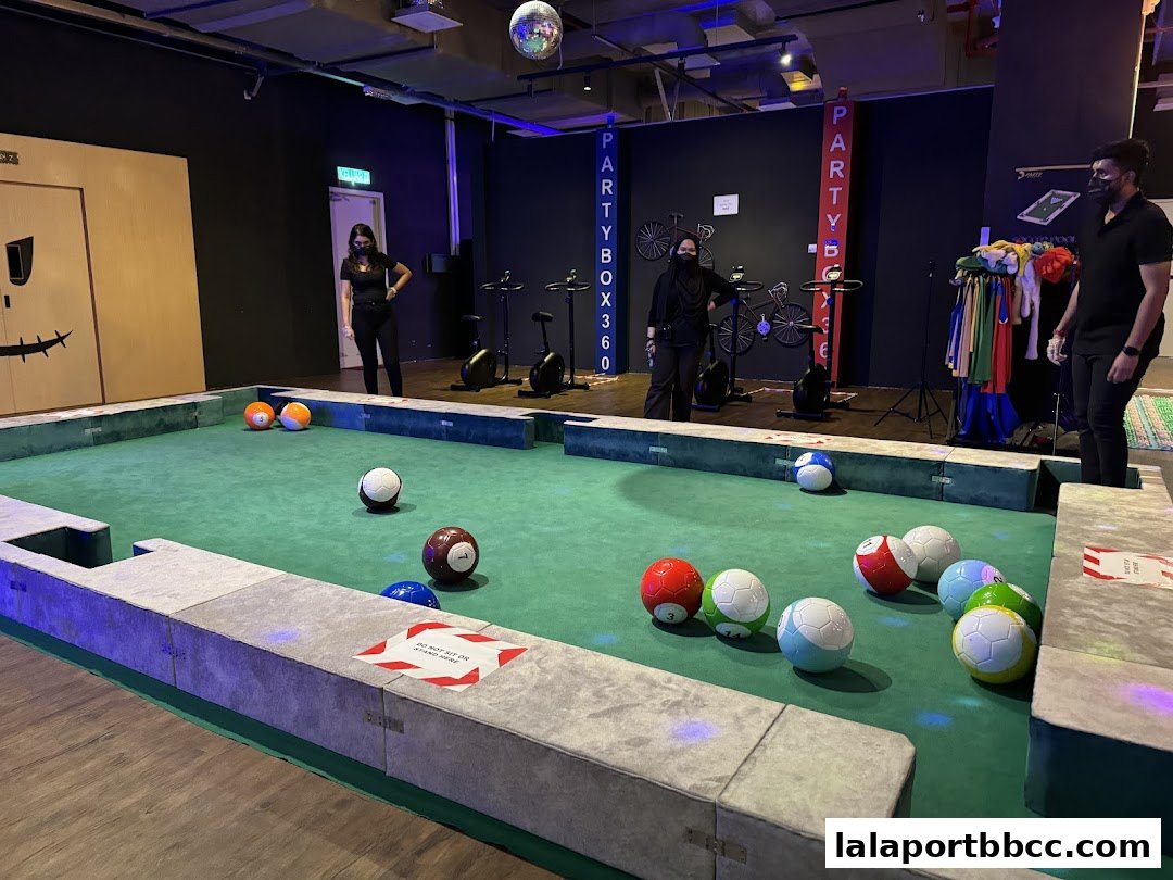 People playing a unique soccer-pool game in a modern entertainment venue.