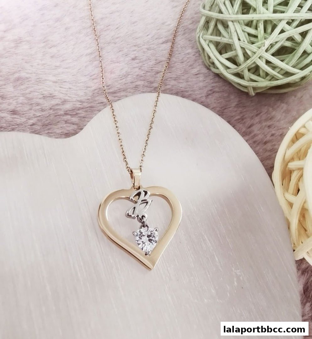 A close-up shot of a gold heart-shaped necklace with a diamond pendant.