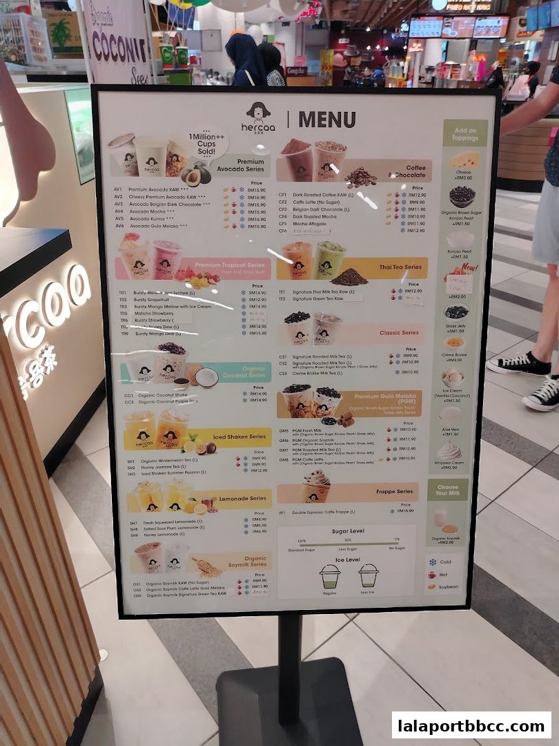 A menu board displaying various drinks from Hercaa, including premium avocado, tropical, Thai tea, and coffee series.