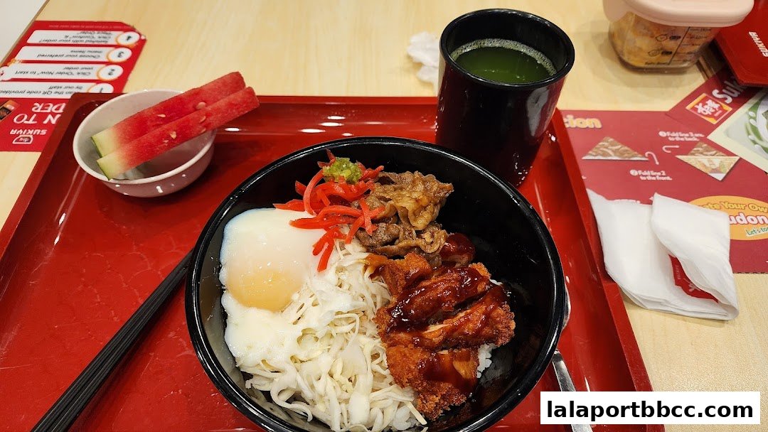 A close-up of a Sukiya meal with rice bowls, chicken, beef, egg, and watermelon.