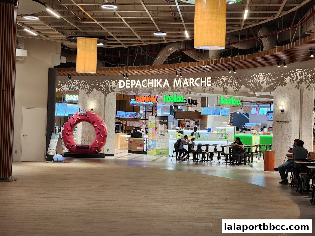 A food hall with various eateries and seating areas, featuring a large donut sculpture.