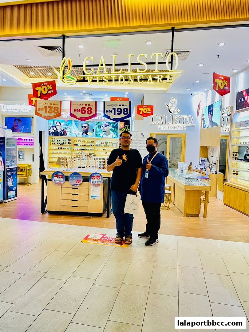 Two men stand in front of the Calisto Vision Care shop, showcasing promotions and eyewear displays.