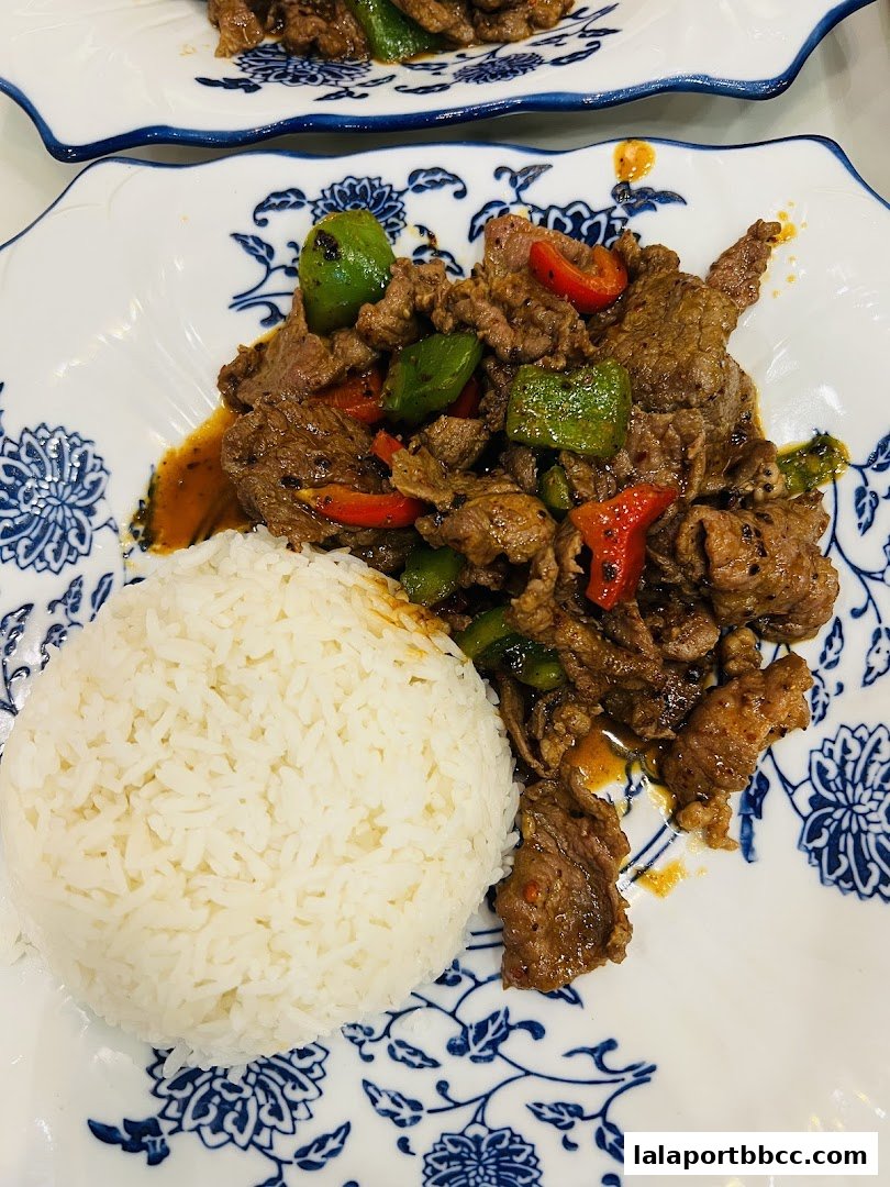 A plate of stir-fried beef with peppers and a side of white rice.