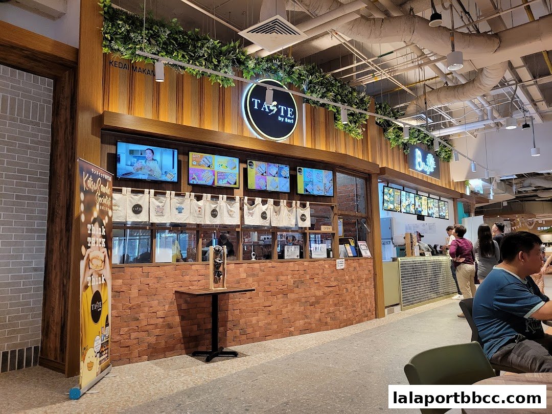 A food court stall with a wooden facade, digital menus, and customers ordering food.