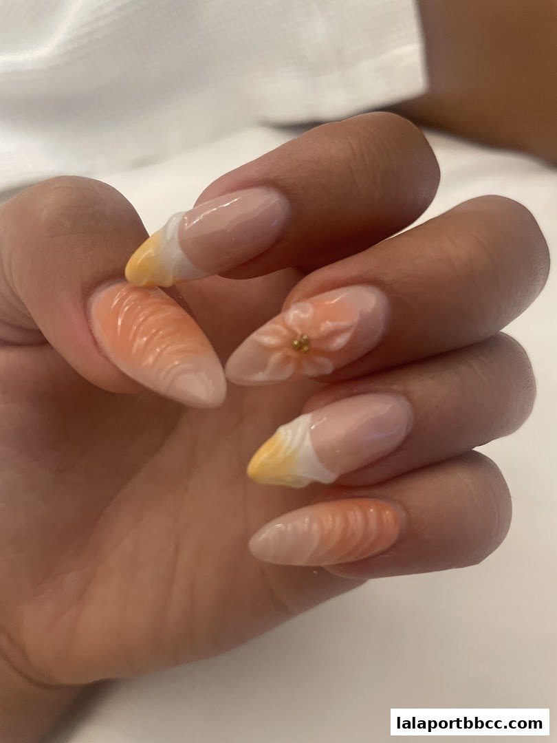 Close-up of a hand with beautifully designed French tip nails featuring orange and yellow accents.
