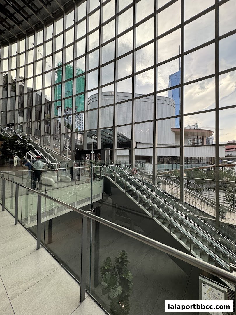 Modern interior with escalators and large glass windows reflecting the cityscape.