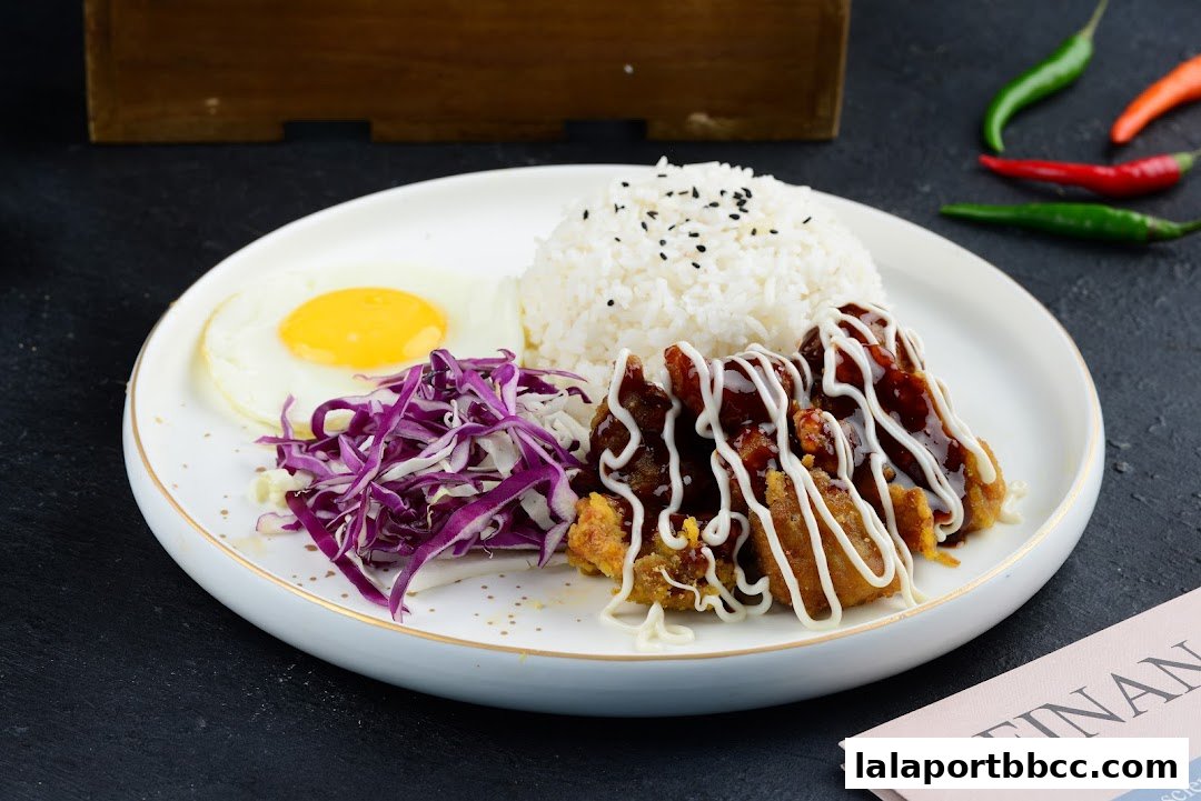 A plate of food with rice, fried chicken, a fried egg, and shredded cabbage.
