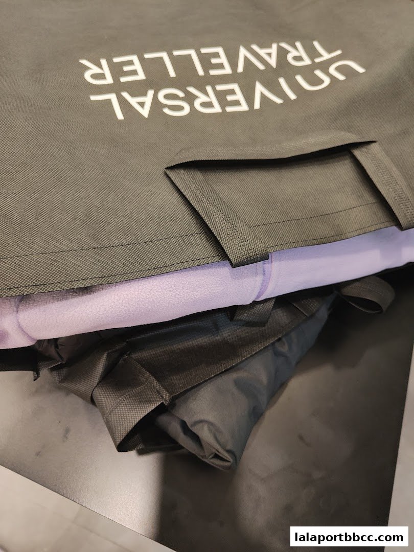 A close-up of a grey tote bag with 'UNIVERSAL TRAVELLER' printed in white.