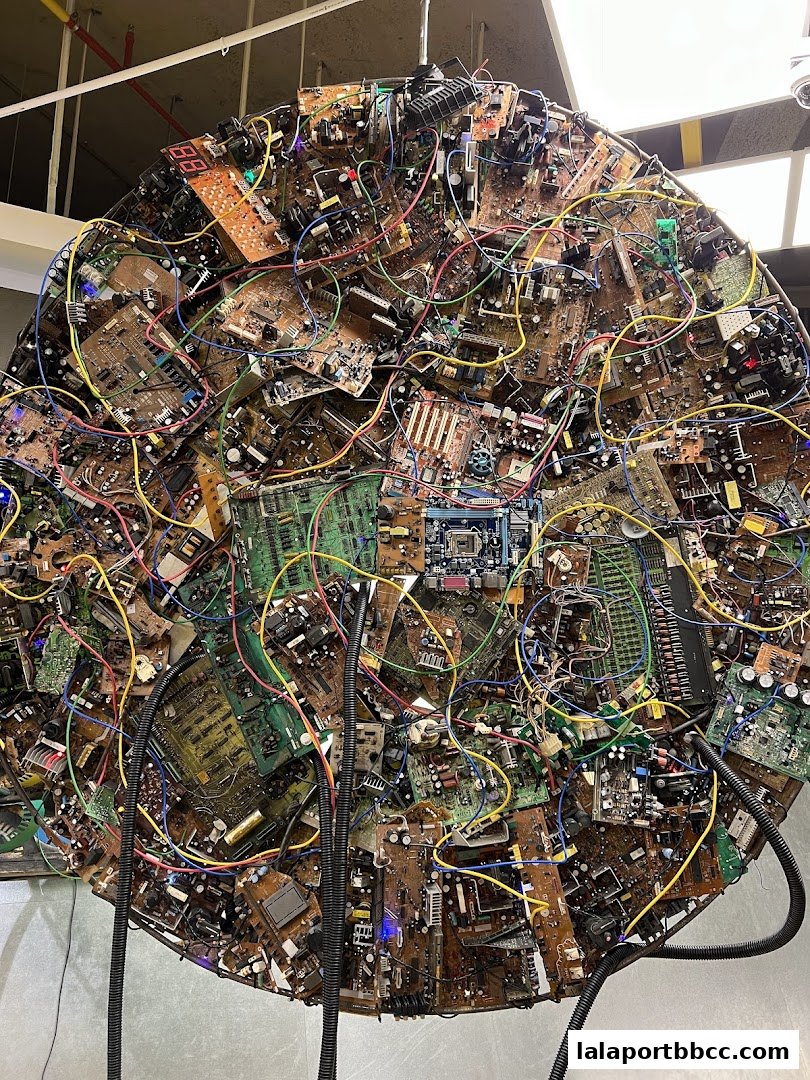 A large, circular art installation made of electronic circuit boards and colorful wires.