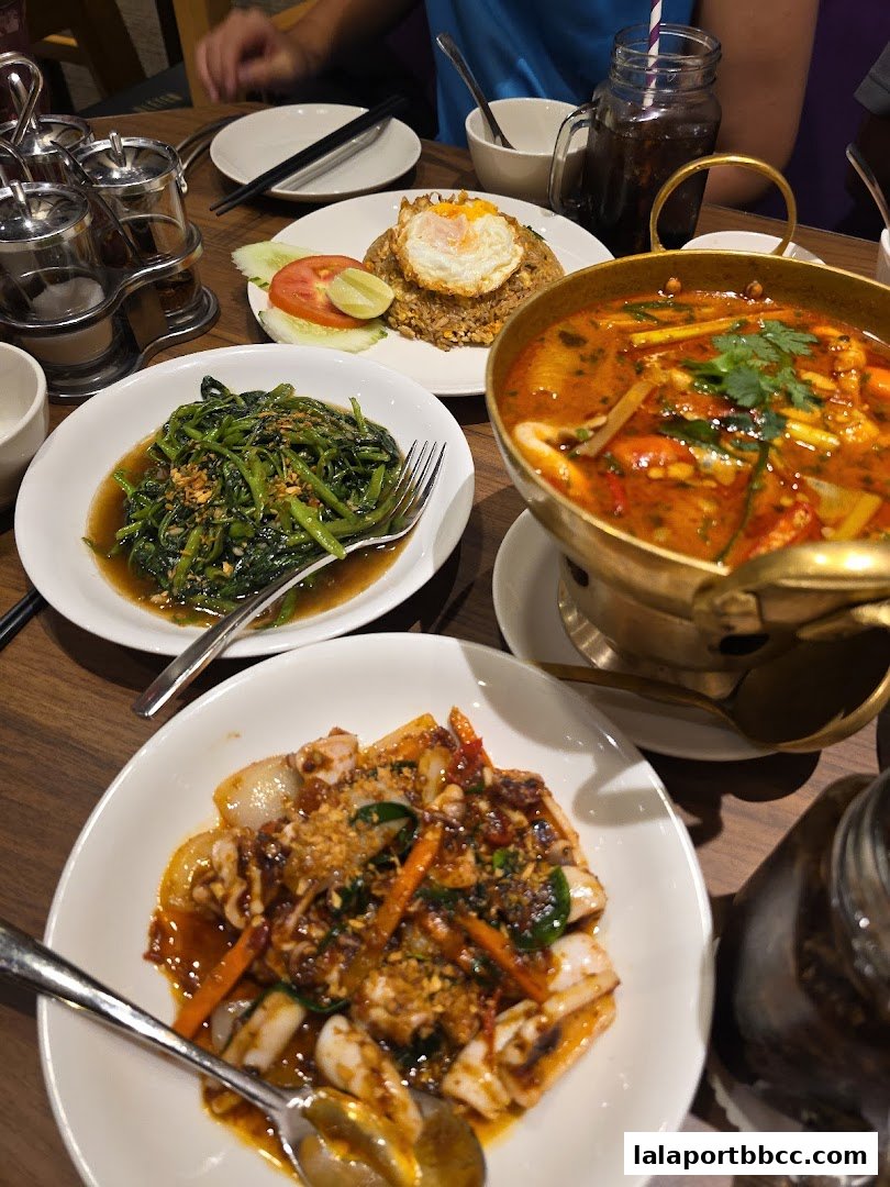 A table laden with delicious Thai dishes, including stir-fried vegetables, fried rice, and a spicy soup.