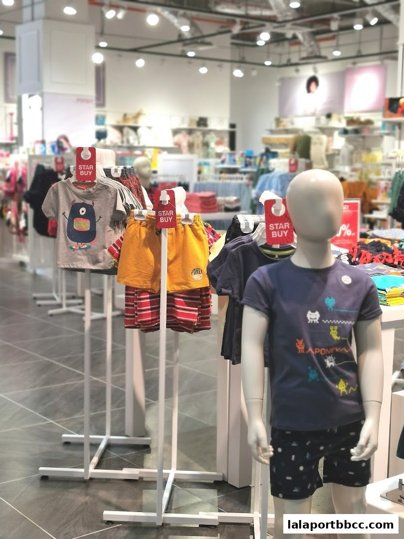 Children's clothing displayed on mannequins and racks inside a bright retail store.