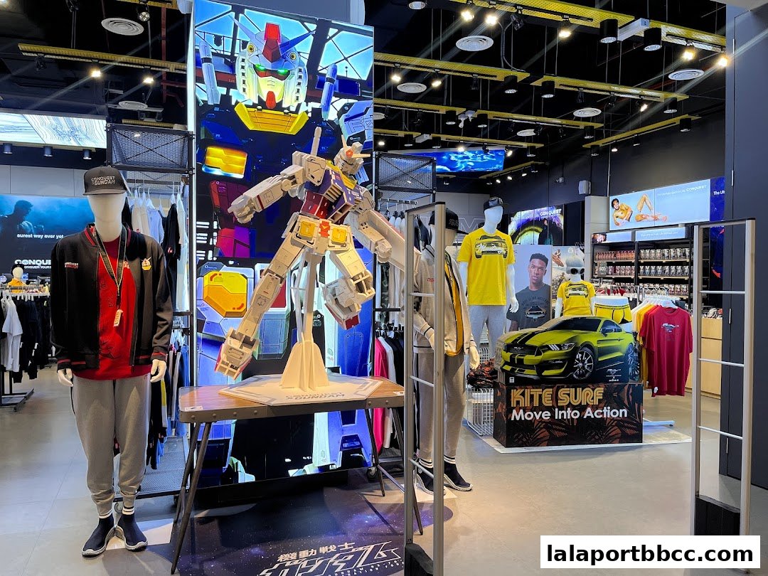 A retail store interior featuring mannequins, apparel, and large displays of a robot and a sports car.