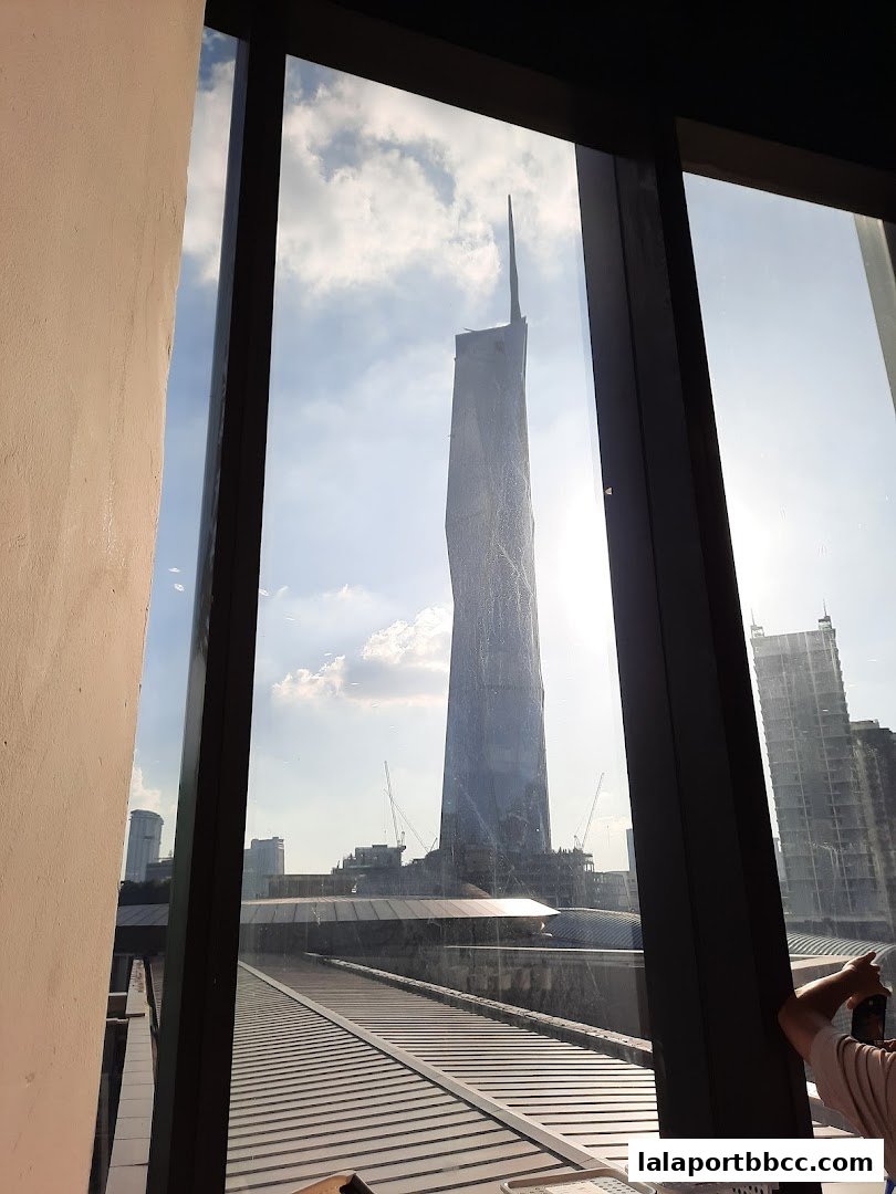 View of a skyscraper under construction through a window with a cloudy sky.