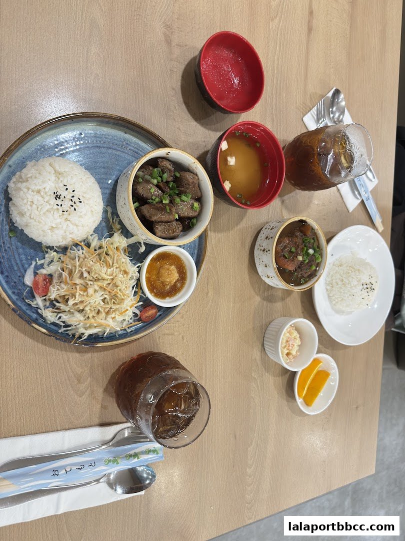 A table setting with two Japanese steak meals, drinks, and side dishes.