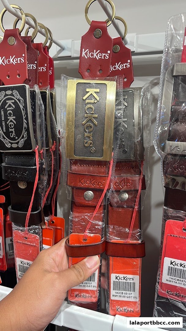 A hand holds a selection of Kickers belts with branded keychains and price tags.