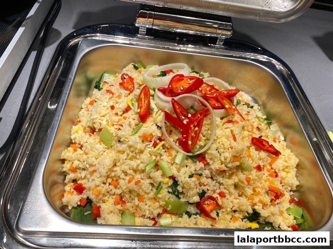 A close-up of a steaming pan of fried rice with chili peppers and onions.