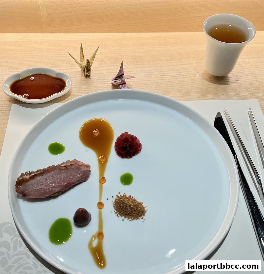 A beautifully plated dish with duck, sauce, fruit, and garnishes, served with tea.
