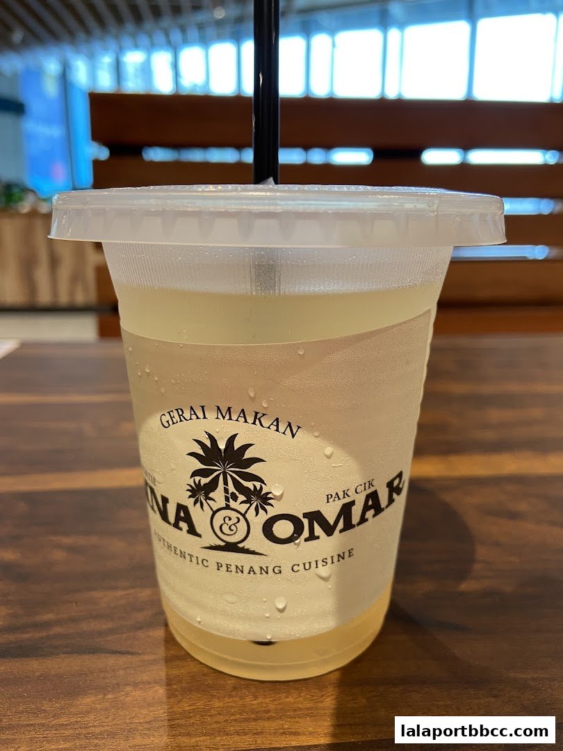 A refreshing drink with the Auntie Anna Pak Cik Omar logo on a wooden table.