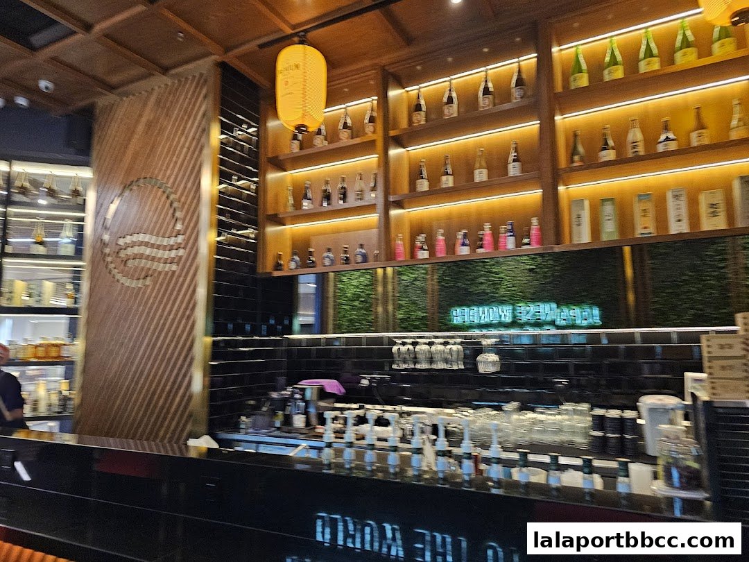 Interior shot of a Japanese restaurant with shelves of sake bottles and a bar.