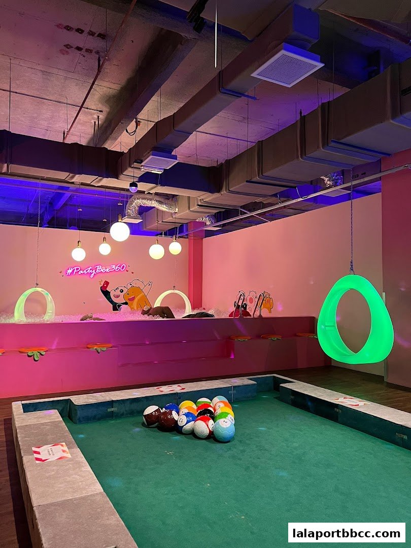 A pool table and ball pit area with neon lights and playful decor.