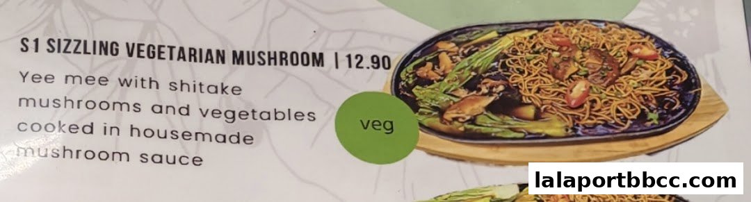 A menu item featuring sizzling vegetarian mushroom noodles with shiitake mushrooms and vegetables.