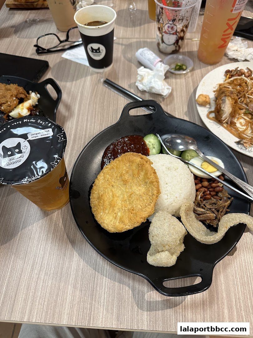 A close-up of Nasi Lemak served with fried chicken, rice, anchovies, and crackers.