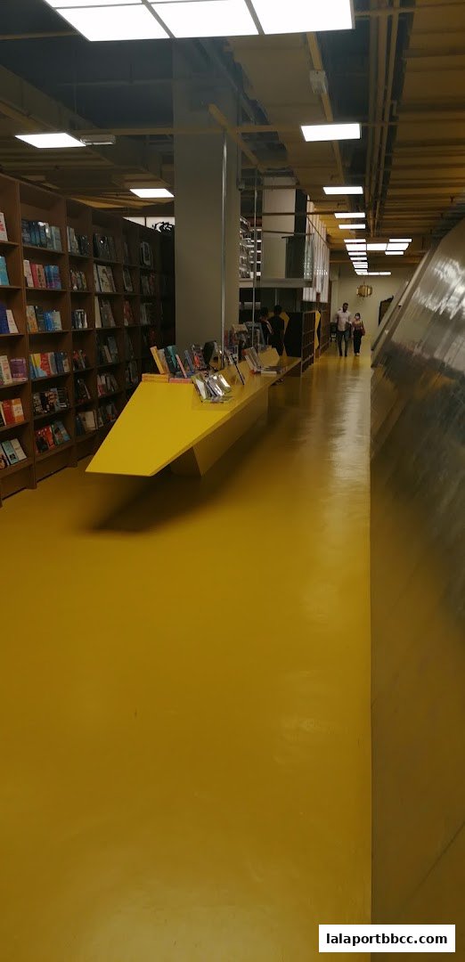 Interior view of a brightly lit store with bookshelves and a yellow display table.