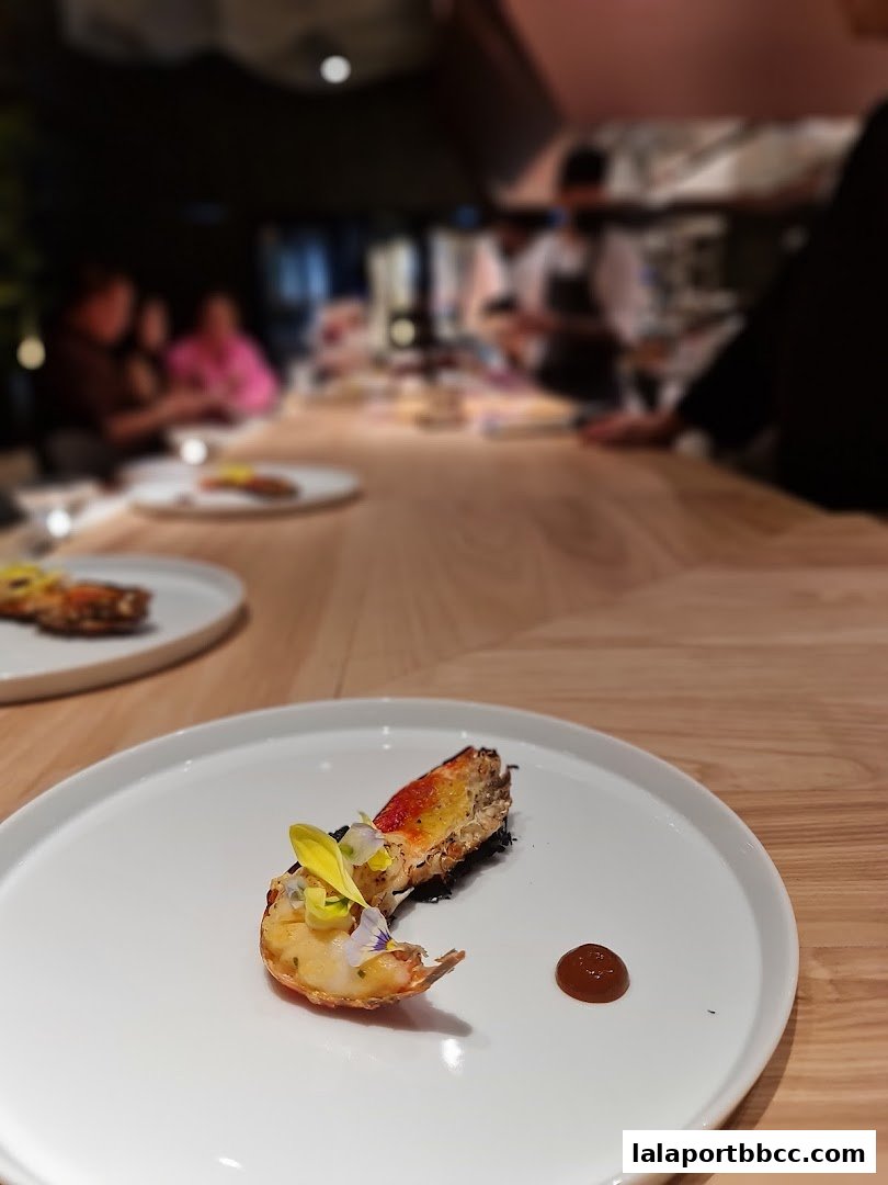 A beautifully plated seafood dish with edible flowers and a sauce on a white plate.