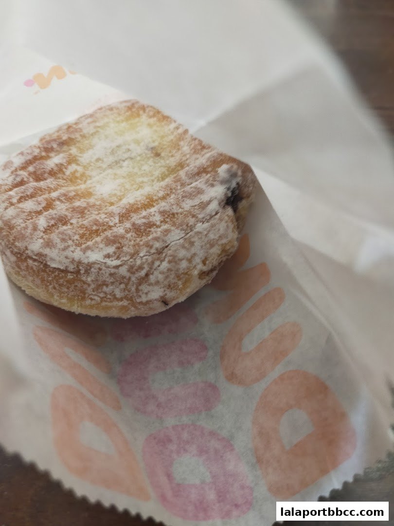 A close-up shot of a powdered donut in a Dunkin' Donuts branded paper bag.