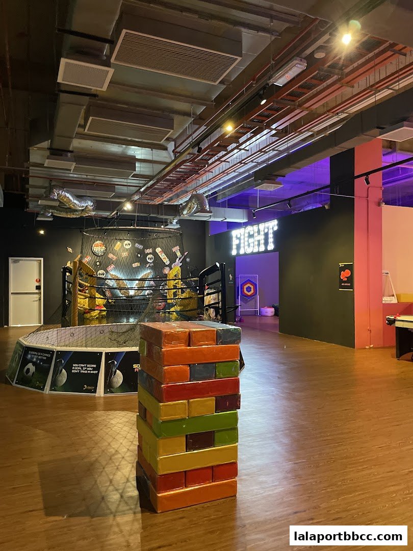 Interior of a fun zone with a giant Jenga game and a boxing ring.
