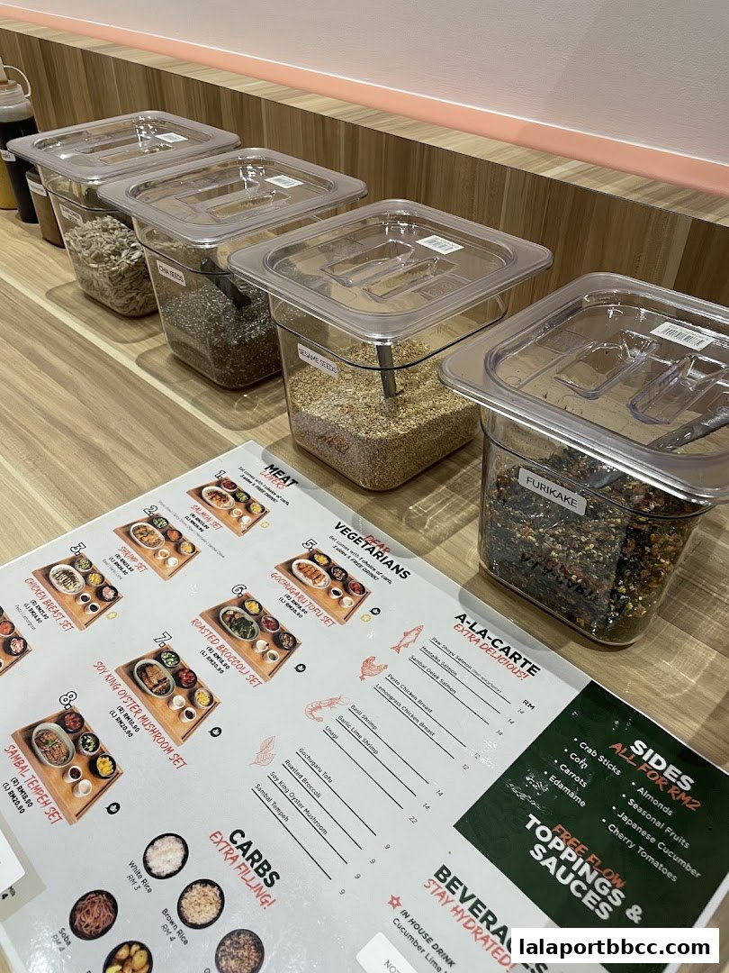 A menu with various sets, a la carte options, sides, and beverages, with ingredients in containers in the background.