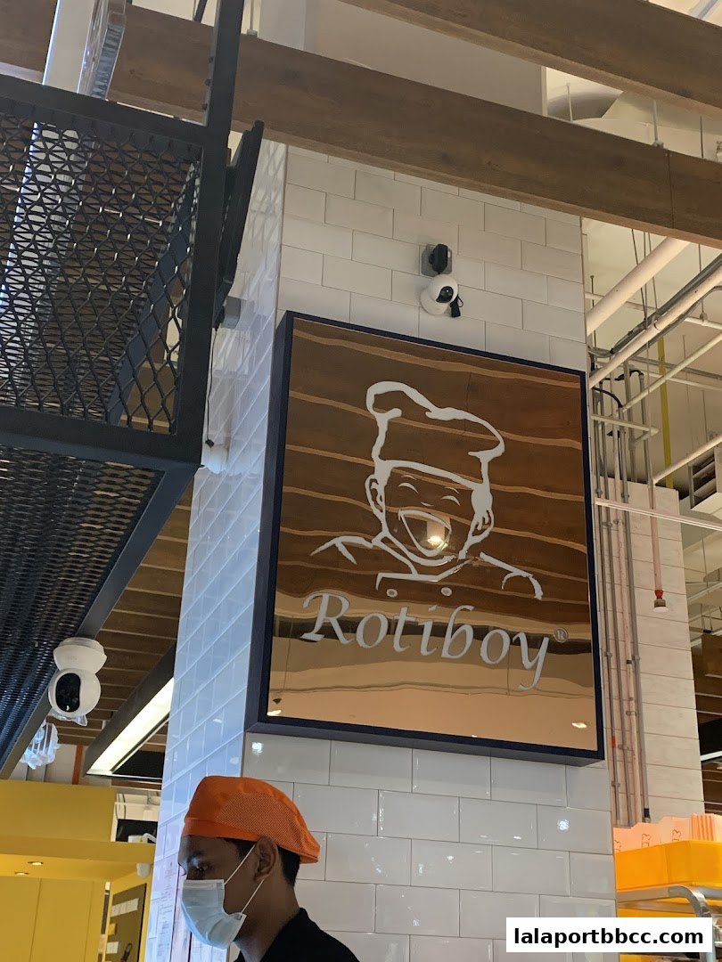 A Rotiboy shop sign with a smiling chef logo and the Rotiboy name.