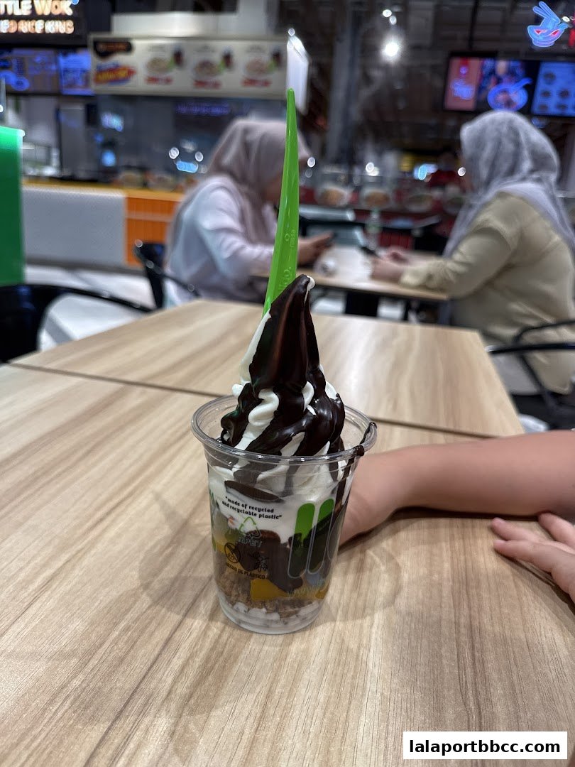A delicious frozen yogurt dessert with chocolate sauce and toppings in a clear cup.