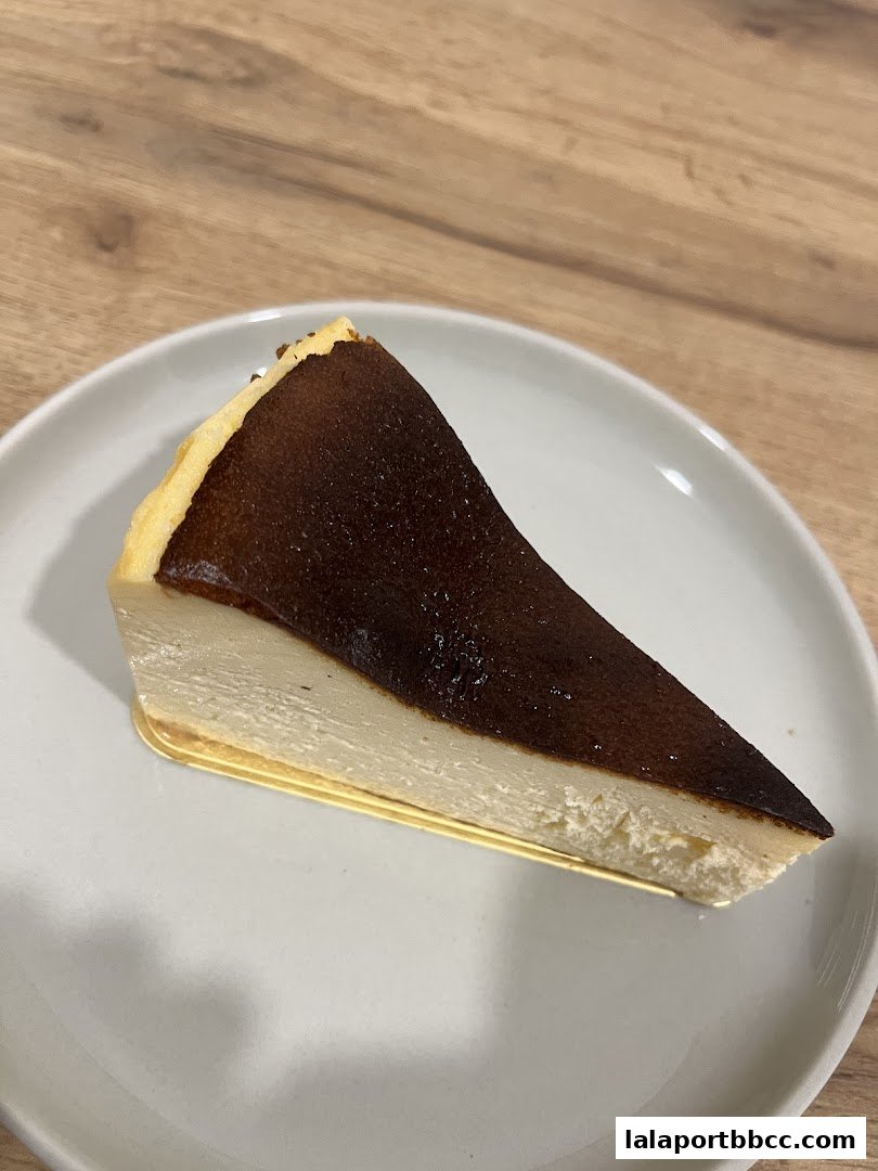 A slice of Basque cheesecake with a caramelized top on a white plate.