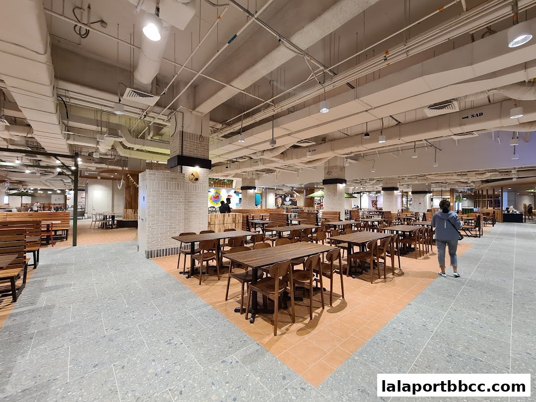 A spacious food court with many tables and chairs, and a person walking away.