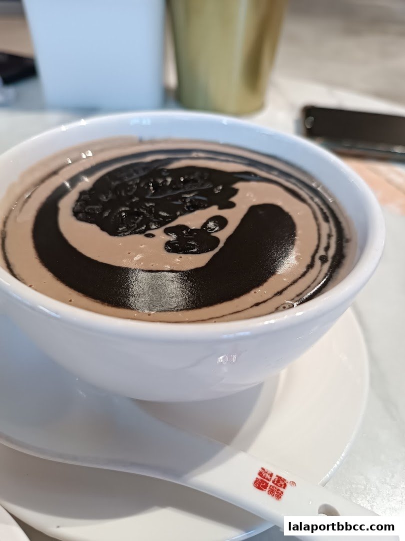 A close-up of a bowl of black sesame dessert with a swirl pattern.