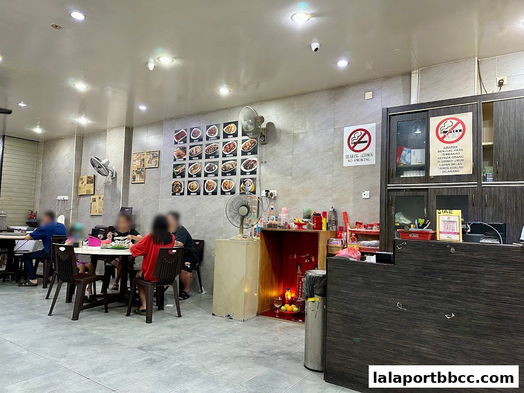 Interior of a restaurant with diners seated at tables and food pictures displayed on the wall.