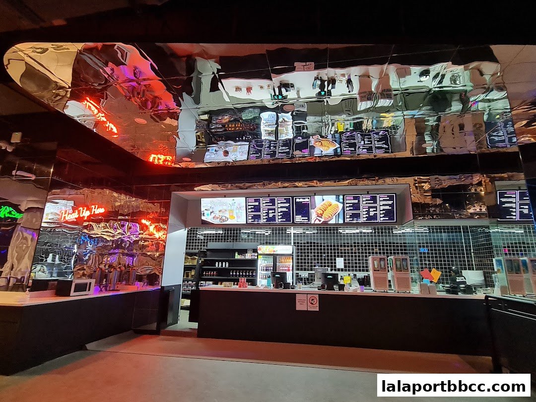 Interior view of a modern food stall with digital menus and a mirrored ceiling.