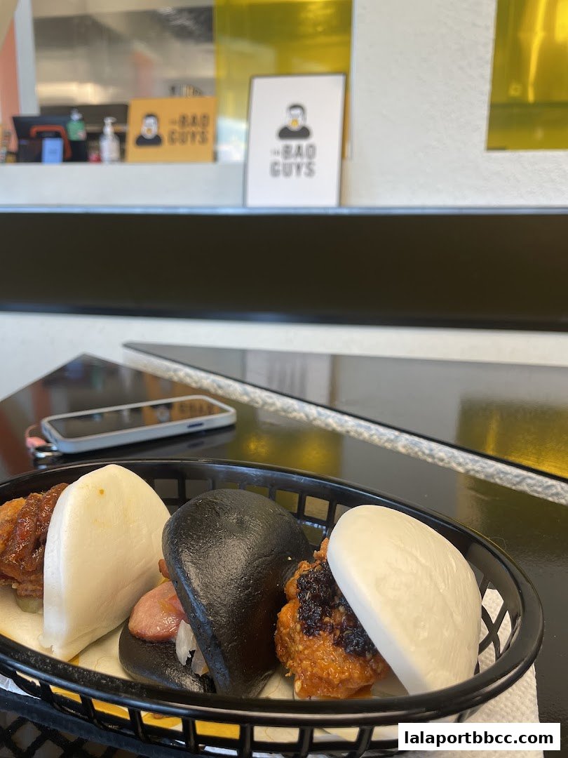 A basket of assorted bao buns with various fillings, including fried chicken and pork.