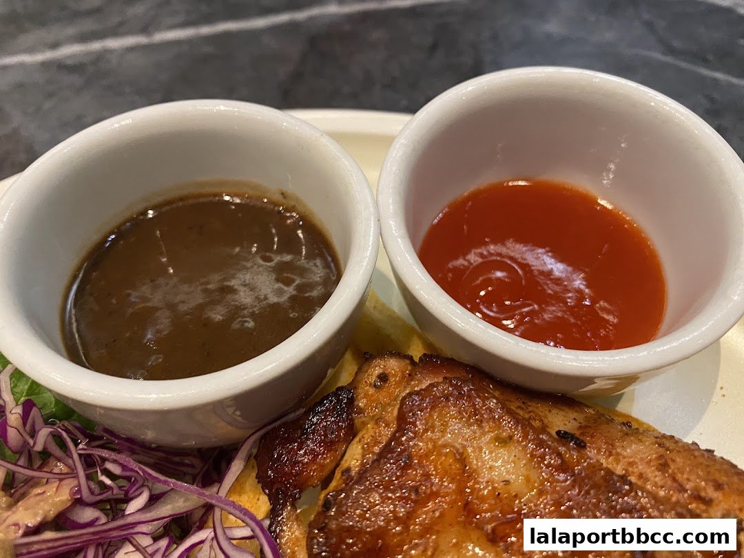 A close-up of a delicious meal featuring grilled chicken, sauces, and a side salad.